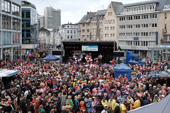 Verkleidete Menschenmenge feiert vor einer Bühne auf dem Bonner Markt