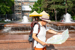 Ein Mann steht vor einem sprudelnden Brunnen und schaut in einen Stadtplan