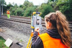 Zwei Mitarbeitende aus dem Amt für Geomanagement und Bodeninformation bei Vermessungsarbeiten an den Bahngleisen