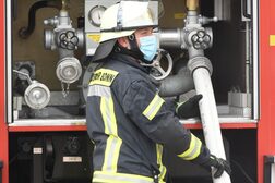 Ein Feuerwehrmann schließt einen Schlauch am Löschfahrzeug an