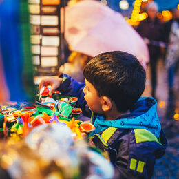 Ein kleiner Junge schaut sich Spielsachen auf dem Weihnachtsmarkt an.