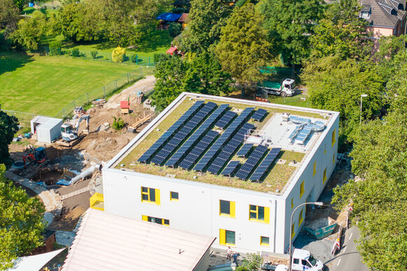 Auf dem Neubau der Kita in der Limpericher Straße wurde eine PV-Anlage (51 kWp) in Kombination mit einer Dachbegrünung installiert. Der durch die PV-Anlagen erzeugte Strom wird überwiegend im Gebäude selbst zur Stromversorgung genutzt. Eventuelle Überschüsse werden in das öffentliche Netz eingespeist.