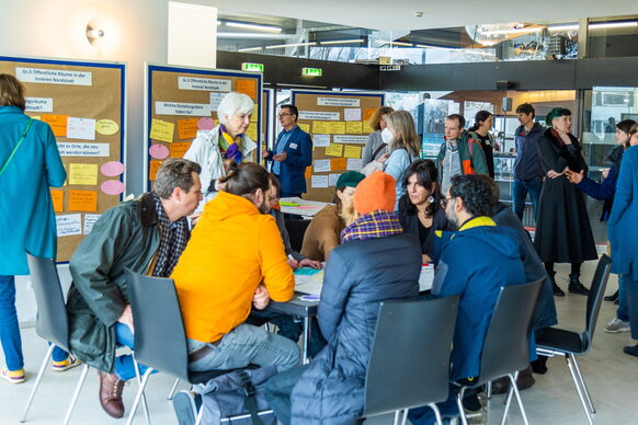 Viele Menschen sitzen an einem Tisch und teilen ihre Ideen für die Bönnschen Viertel.