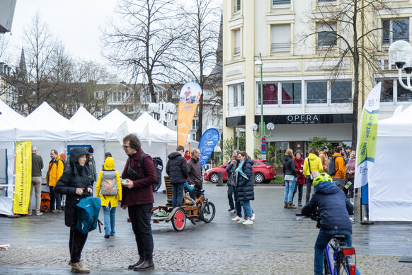 Auf dem Vorplatz der Oper sieht man Kinder und Erwachsene, die sich an Informationsständen unterhalten.