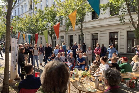 Das Bild zeigt eine Mitarbeiterin der Stadtverwaltung, die rund 30 Menschen in der Inneren Nordstadt Ideen für neue Mobilität erläutert.