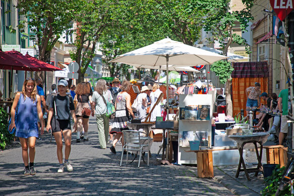 Das Bild zeigt eine sonnenbeschienene Altstadt-Straße mit Ständen und Menschen am Tag der Bönnschen Viertel.