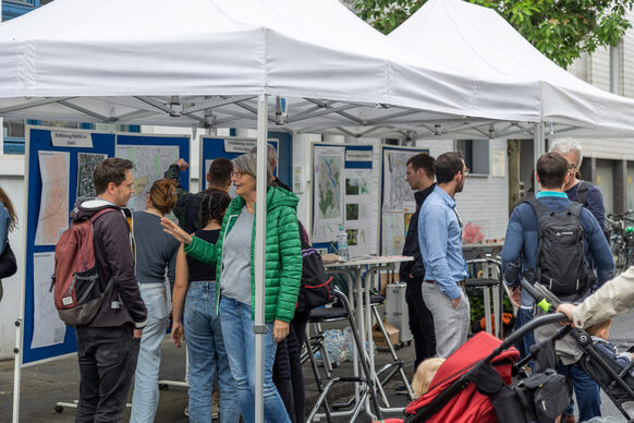 Das Bild zeigt einen Stand in einer gesperrten Straße im Combahnviertel, an dem sich mehrere Menschen unterhalten.