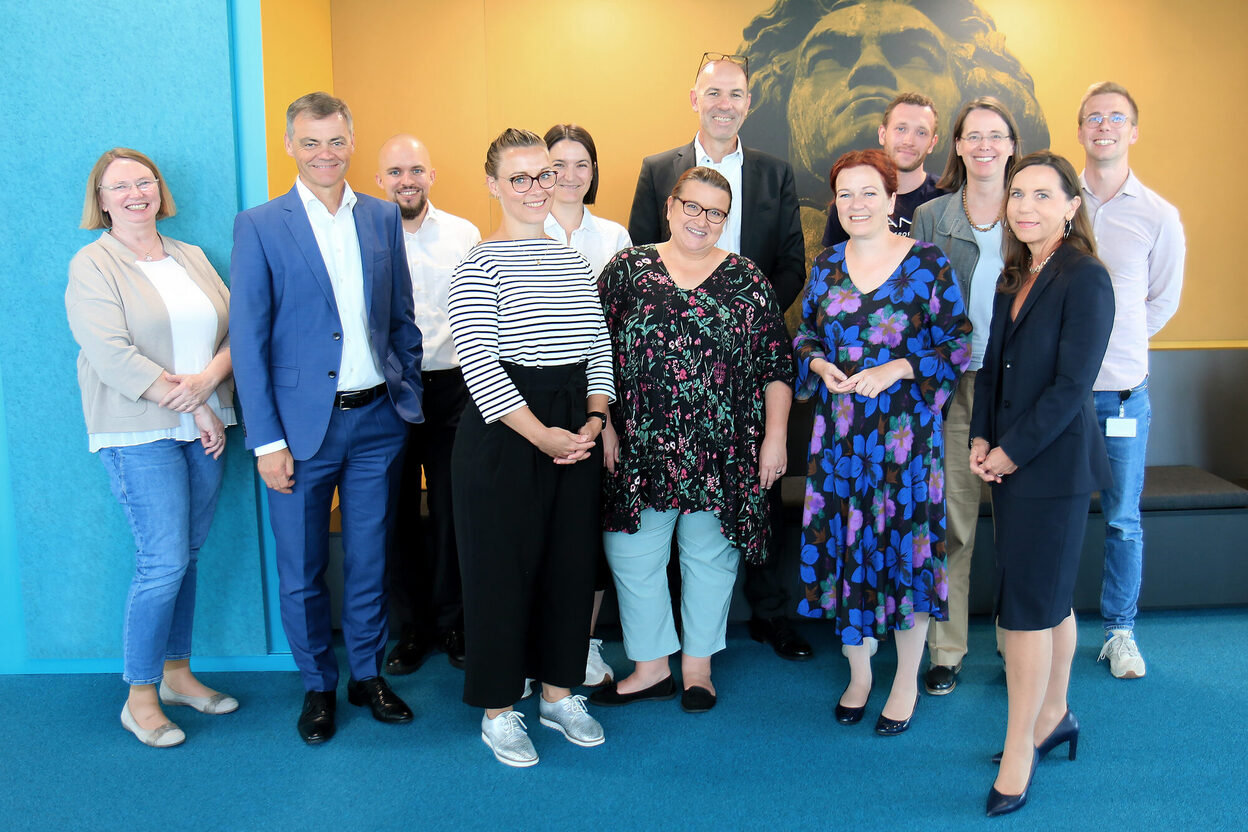 Das Bild zeigt OB Katja Dörner (im Blumenkleid) mit Führungskräften und Mitarbeitenden des Unternehmens Conet.