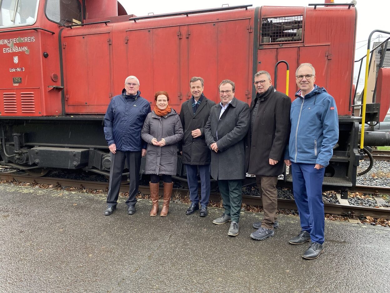 Übergabe des Förderbescheids für die geplante Stadtbahn Niederkassel. Sechs Personen vor einem Zug.