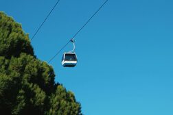 Zwei Kabinen einer Seilbahn vor blauem Himmel