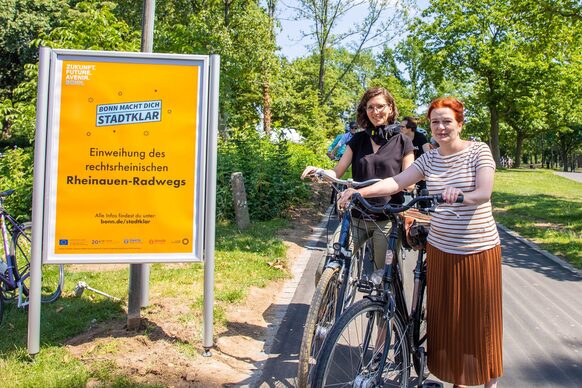 OB Dörner und BBM Mohn neben einem Plakat, das auf den ausgebauten Radweg aufmerksam macht.