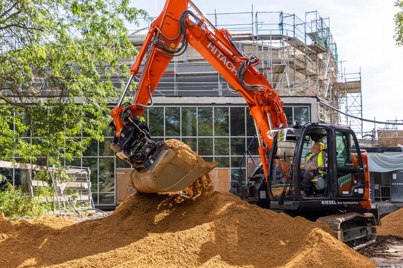 Ein Bagger steht an einem riesigen Sandhügel vor der Beethovenhalle.