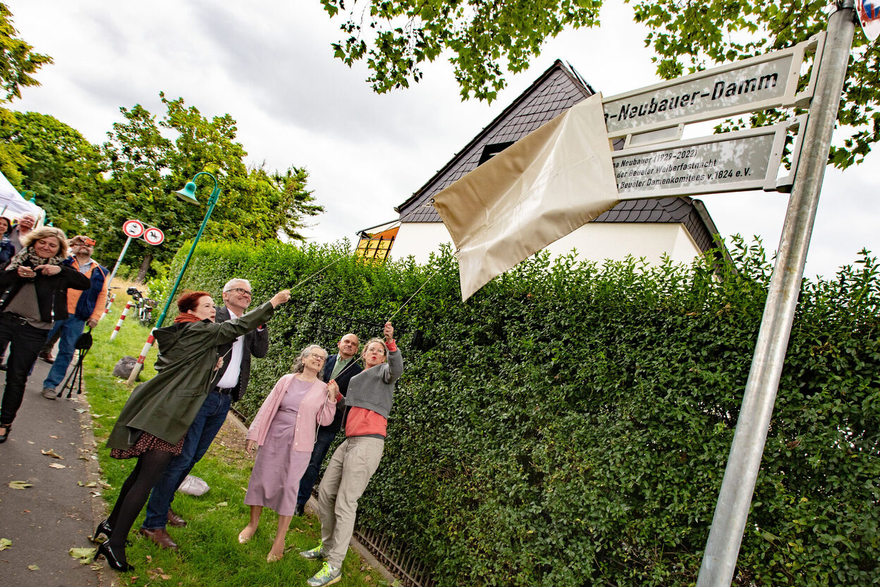 Mehrere Personen enthüllen das neue Straßenschild am Erna-Neubauer-Damm.