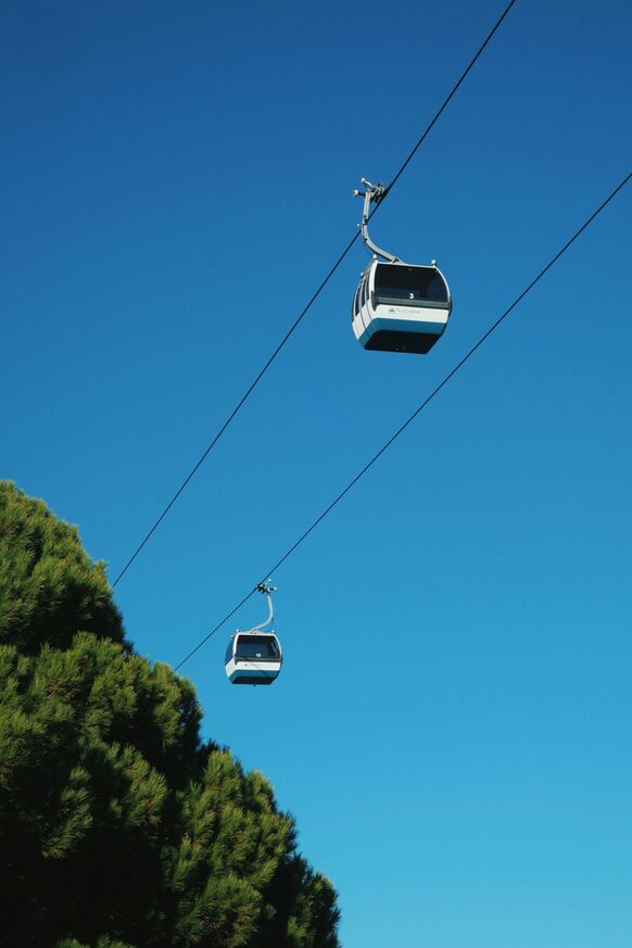 Zwei Kabinen einer Seilbahn vor blauem Himmel