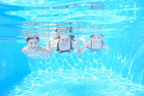 Unterwasseraufnahme von drei im Schwimmbad tauchenden Frauen