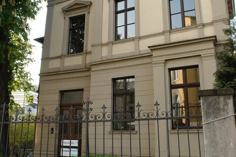 Altbau-Haus mit grau-weißer Fassade.