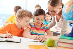 Eine Lehrerinnen erklärt Grundschülern eine Aufgabe