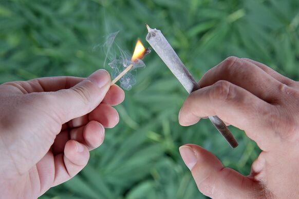 Hände mit Joint und Streichholz