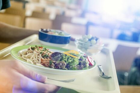 Eine Person trägt ein Tablett mit Essen