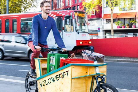 Ein Mann fährt mit seinem Lastenfahrrad durch die Stadt