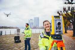 Zwei Mitarbeitende aus dem Amt für Geomanagement und Bodeninformation bei Vermessungsarbeiten am Rheinufer