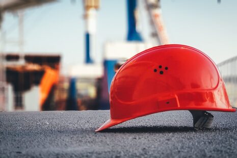 Ein roter Schutzhelm liegt auf einer Baustelle auf dem Boden