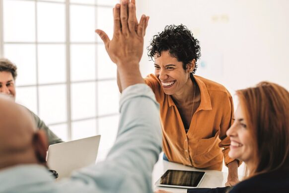 Lächelnde Kolleg*innen bei einem "High Five" im Büro