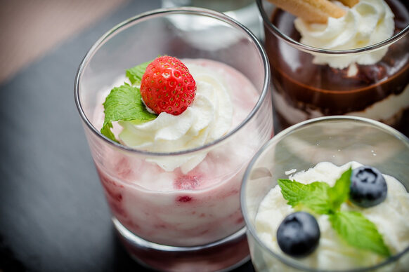 Rosafarbenes Früchtedessert in kleinen Gläsern, garniert mit Brombeeren