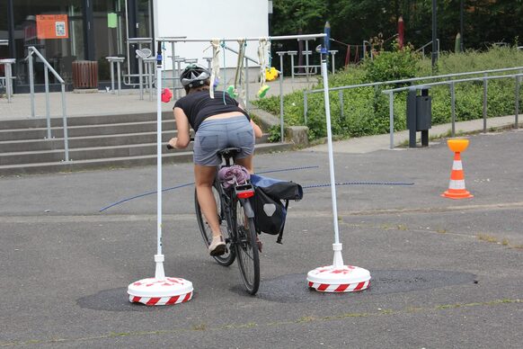 Eine Radfahrerin fährt unter einem Hindernis durch.