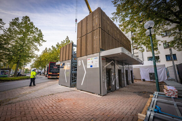 Das Bild zeigt einen Krann, der ein Fertigbau-Modul in Bonn-Beuel am Bahnhof hochzieht. So entsteht ein neues Parkhaus für Fahrräder.