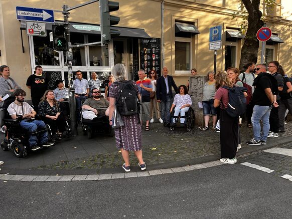 Das Bild zeigt eine Gruppe von rund 15 Menschen, die sich im Rahmen des Fußverkehrschecks an einer Straßenkreuzung unterhalten.