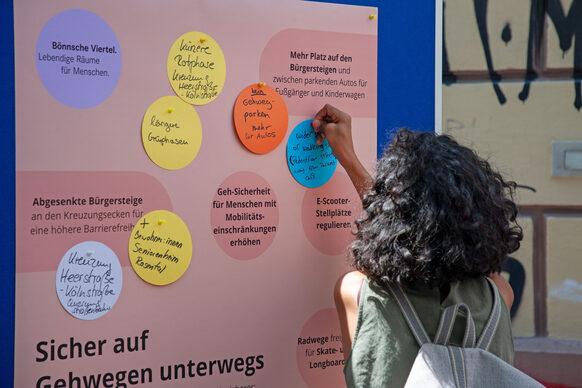 Frau pinnt bunte Notizen an eine Infowand