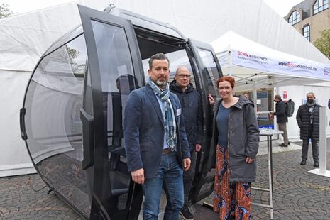 Oberbürgermeisterin Katja Dörner, Baudezernent Helmut Wiesner und Projektleiter Dirk Delpho an der Seilbahnkabine vor dem Zelt der Infomesse auf dem Münsterplatz