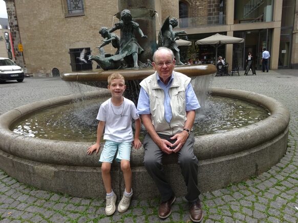 Großvater und Enkel sitzen am Martinsbrunnen in Bonn